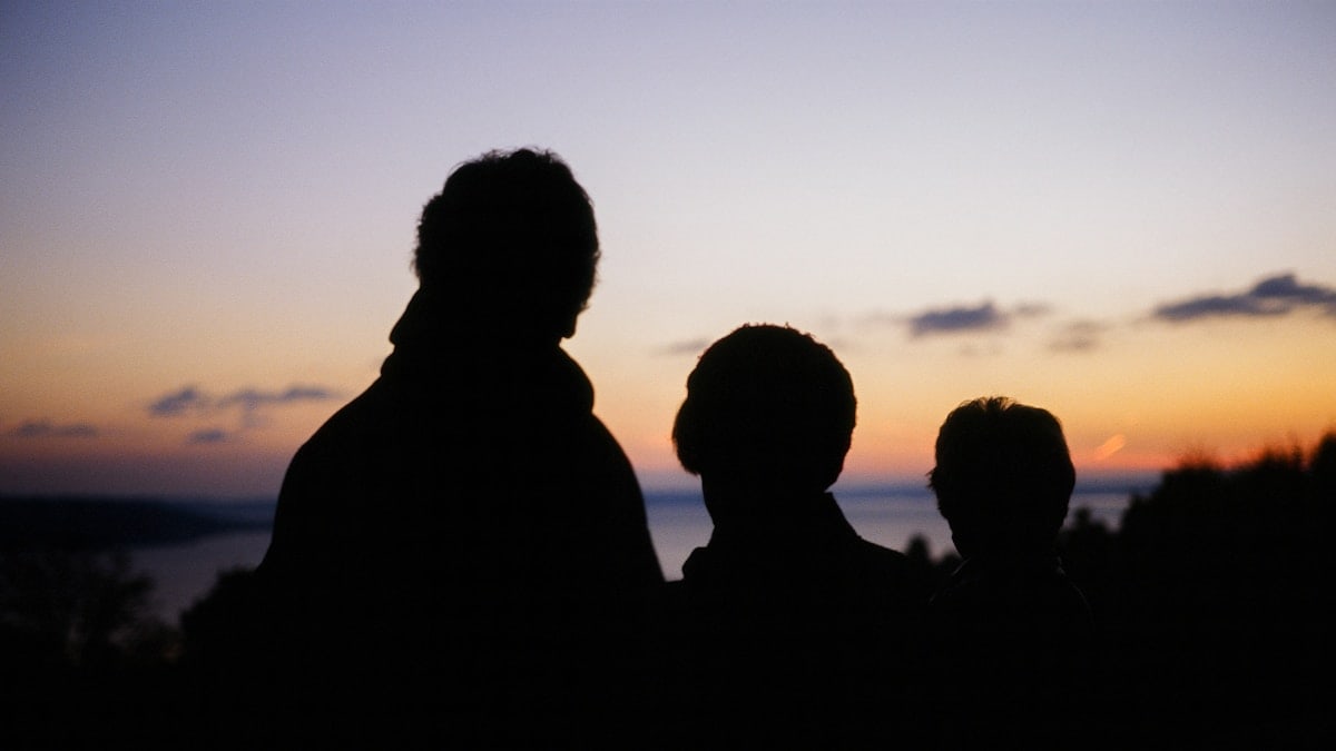 silhouette of people standing in front of a sunset